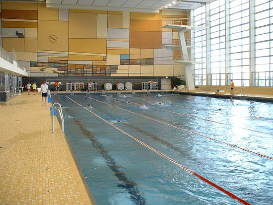 Schwimmerbecken mit Schwimmbahnleinen, Startsockel und Sprungturm.