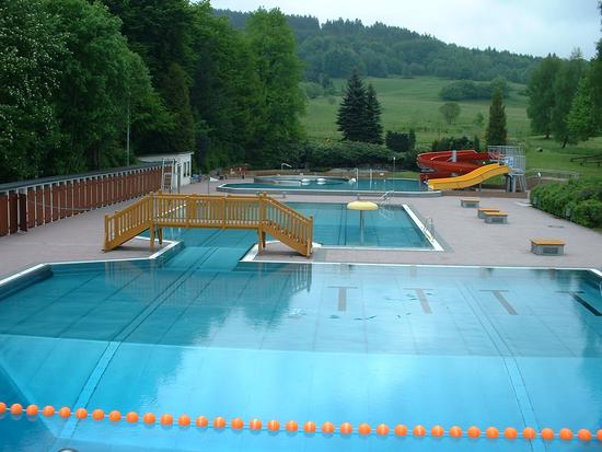 Mehrzweckbecken mit Sprungbereich im Schwimmerteil. Im Hintergrund Erlebnisbecken mit Rutschenanlage.