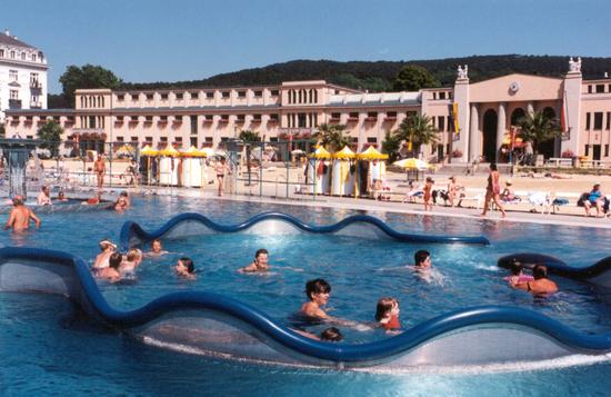 Blick vom Mineralwasserbecken auf die historischen Gebäude.
Im Vordergrund eine Wasserschlange zur Attraktionssteigerung.